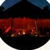 A traditional open-sided ceremonial house lit at night.